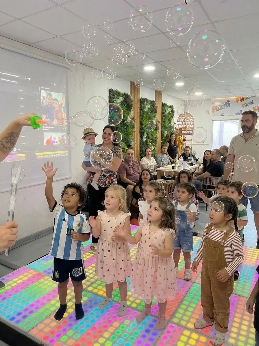Chicos jugando con burbujas sobre la pista LED de FLIKITI, con las familias de fondo